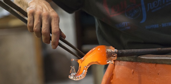 Man working with molten glass using a tweezers in glass factory, Murano, Venice, Veneto, Italy