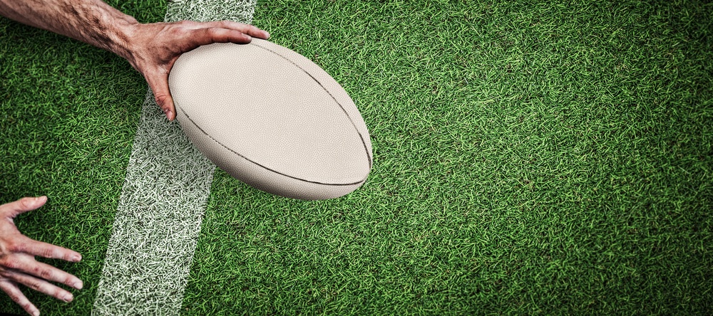 Cropped,Image,Of,A,Man,Holding,Rugby,Ball,Against,Pitch